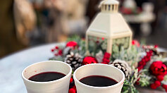 Mulled wine in disposable paper cups on table at Christmas market. Winter holidays, hot drinks and Christmas time concept